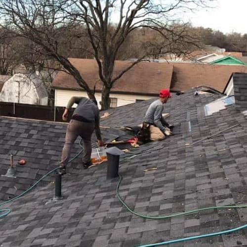 Roofers repair a shingle roof.