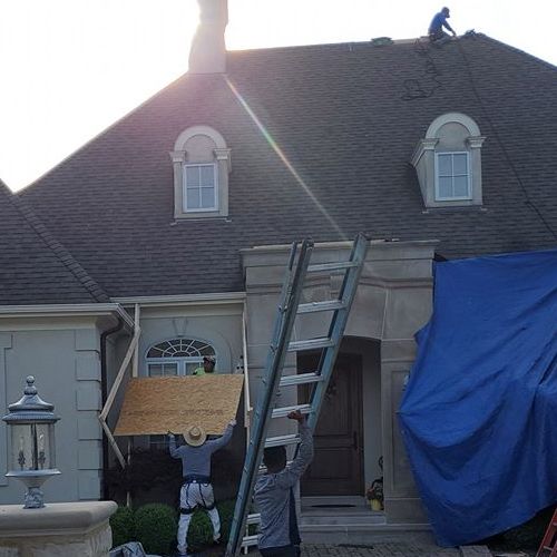 Roofers work on emergency roofing solutions.