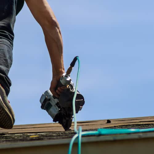 Roofer nails in shingles
